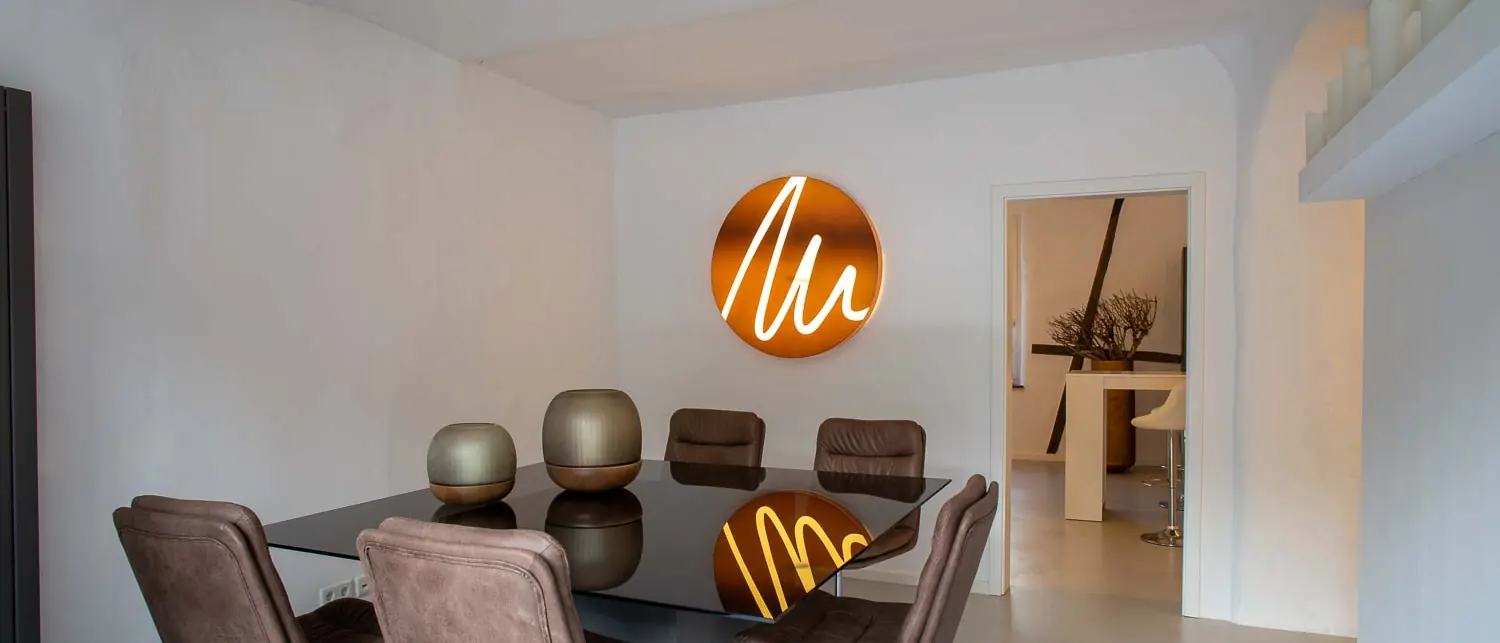 Beratungsraum der Praxis Schönheitsmühle mit beleuchtetem Signet an der Wand